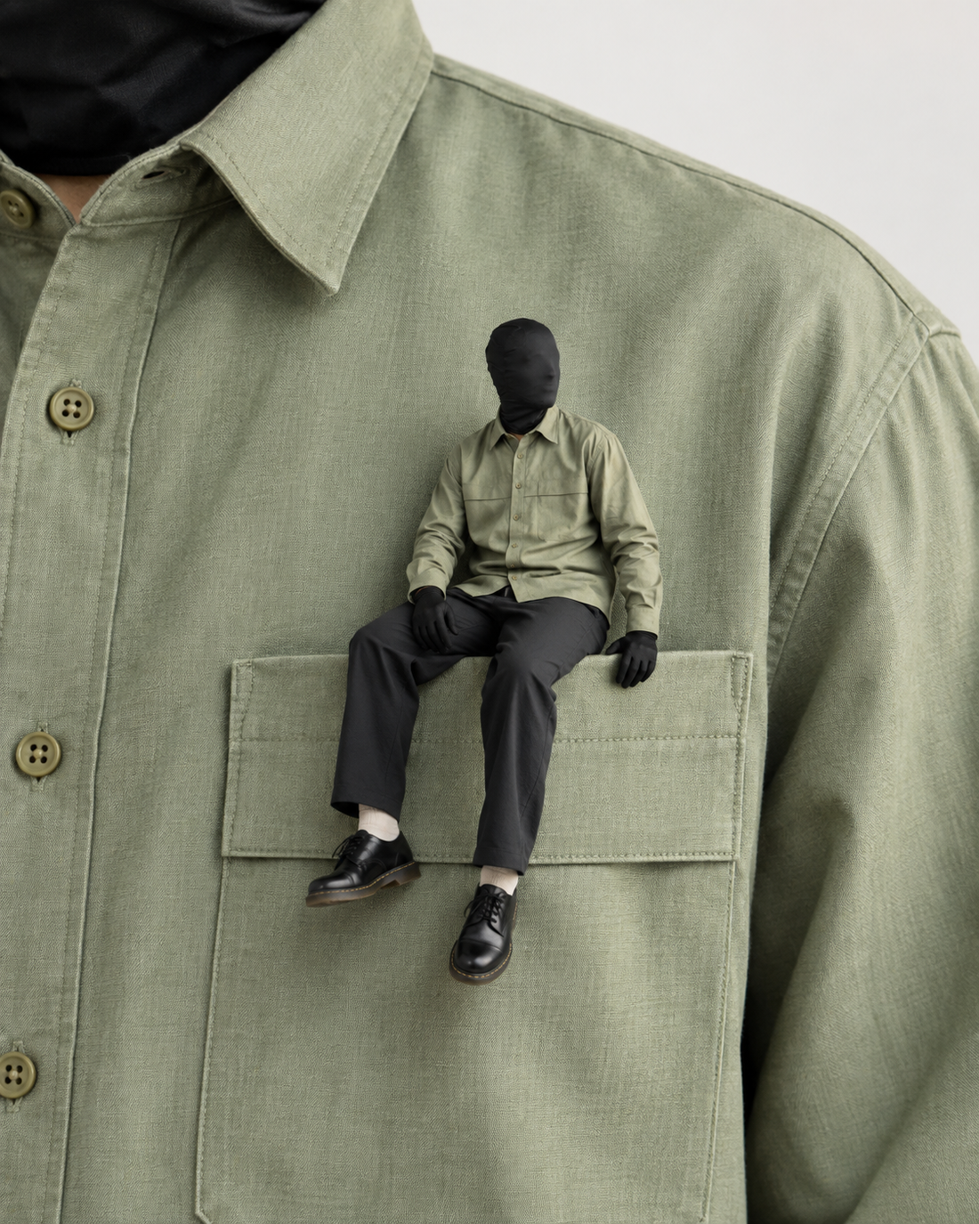 Men’s fashion editorial featuring an olive green shirt with a miniature seated model